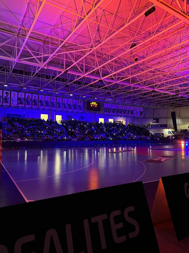 Salle Mangin Beaulieu avec un jeu de lumière tamisée lors d'un match record de fréquentation pour le Nantes Métropole Futsal, grâce à l'expertise de Morgane Ease en stratégie de remplissage de salle et optimisation de la billetterie.